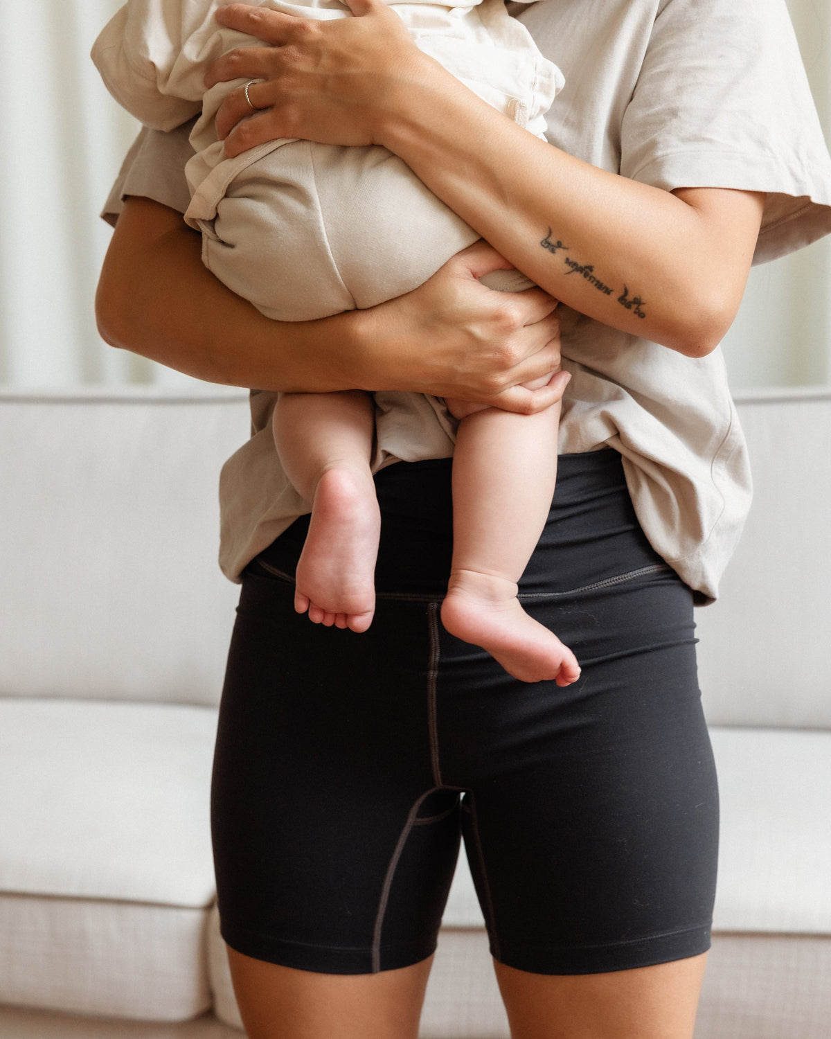 Woman wearing the Embodie Renew Short while holding her baby