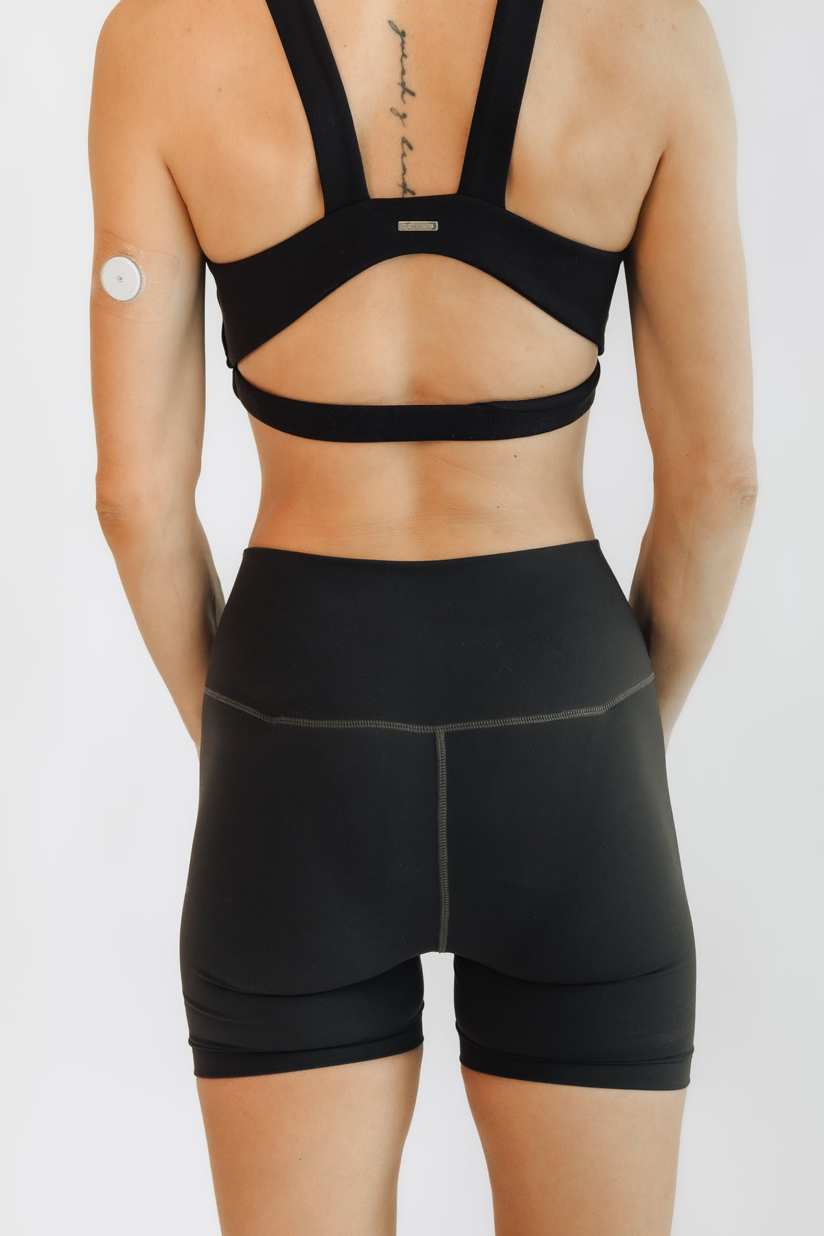 Woman wearing the black Embodie Renew Short, shown from the back to highlight the high-rise waistband and full-coverage fit.